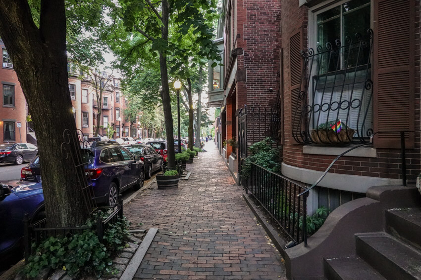 A street in the city of Boston, with adequate shade provided by the many trees on the footpath. The footpath is brick paved.