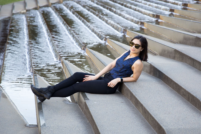 Me sitting on concrete steps next to a water feature, leaning back with my sunglasses on