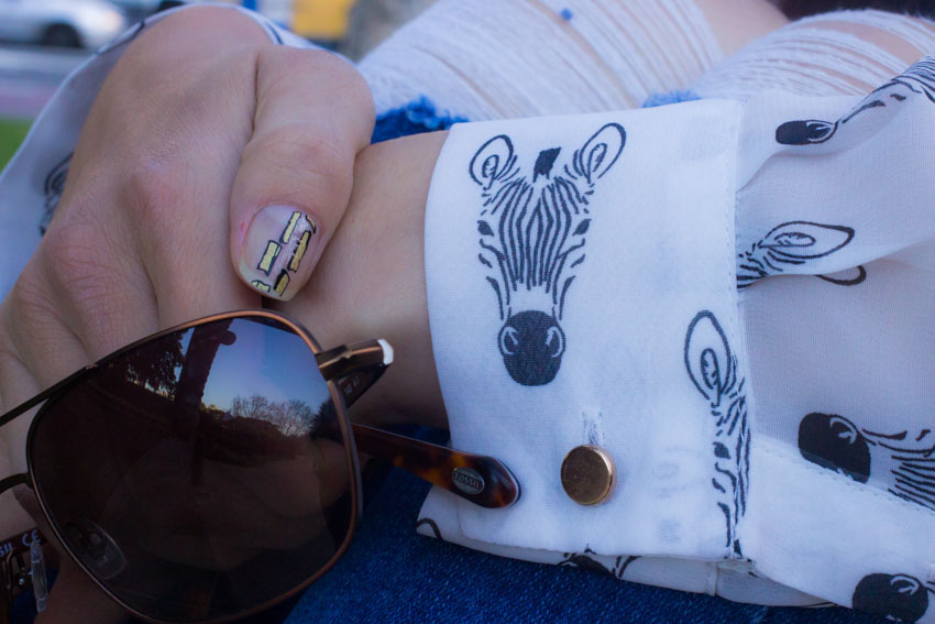 Close up of my hand, showing the print on my sleeve, my sunglasses and the nail art on my thumbnail