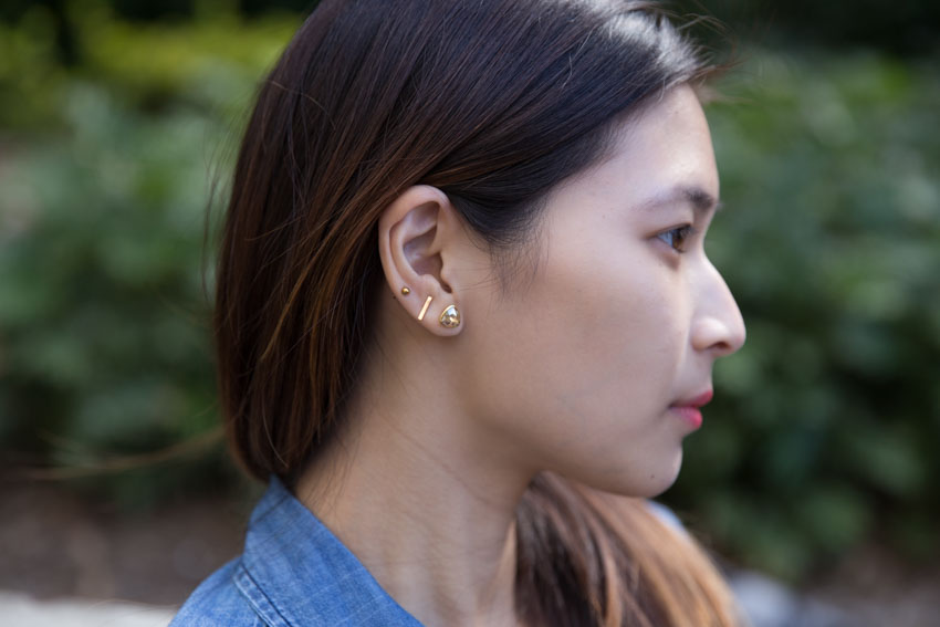 Close up of my small rose gold ball stud and bar stud earrings and my triangular gold earring with coloured stone