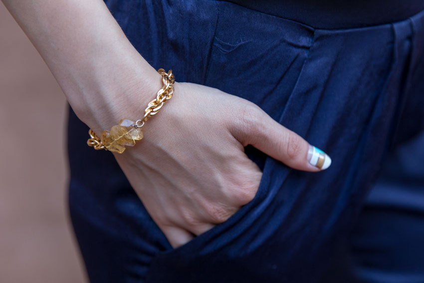 Close up of gold chain bracelet with yellow crystals, with my hand in my pocket