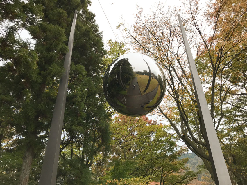 A large metallic sphere suspended between two cables between two poles