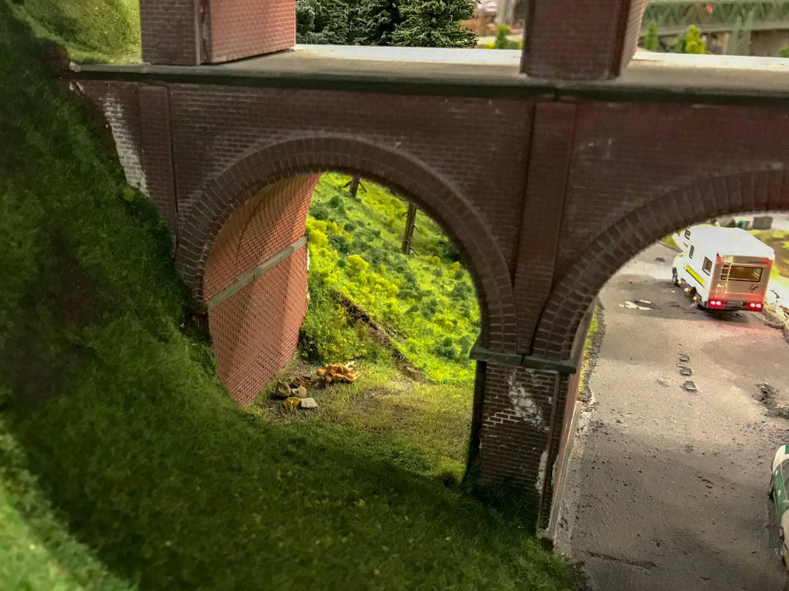 Miniature figurines romping in the grass, under the arches of a bridge