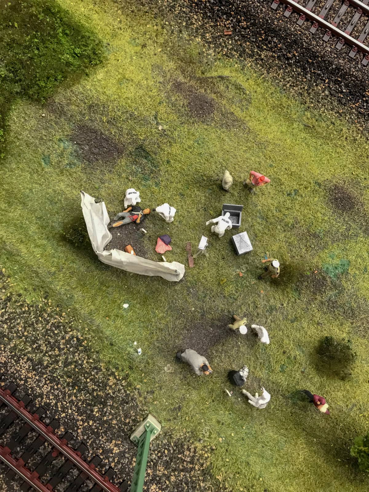A birds-eye view of figurines near railtracks, assembled with props like a murder scene