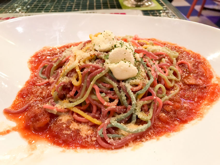 Colourful spaghetti with grated cheese and red tomato pasta sauce on a white plate