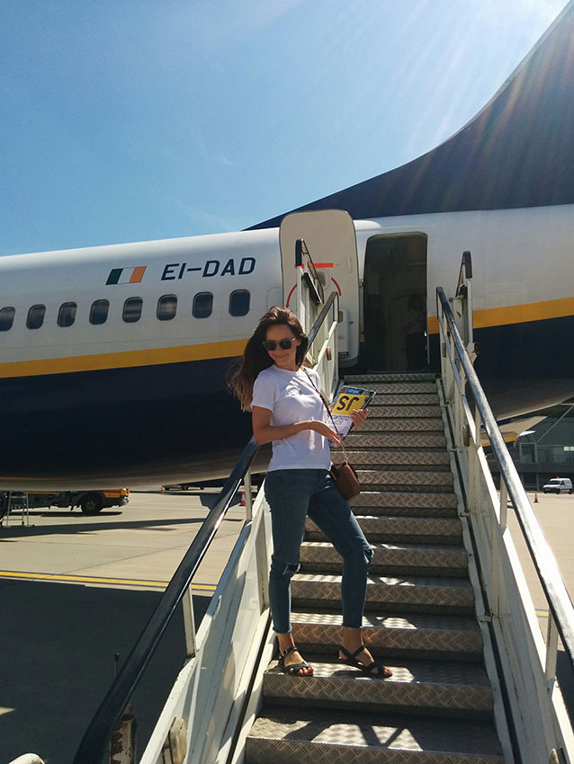 Amy on the steps to a plane, travelling with her JavaScript books