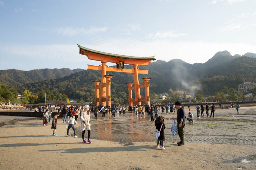 The shrine with a lot of people walking around in the wet sand