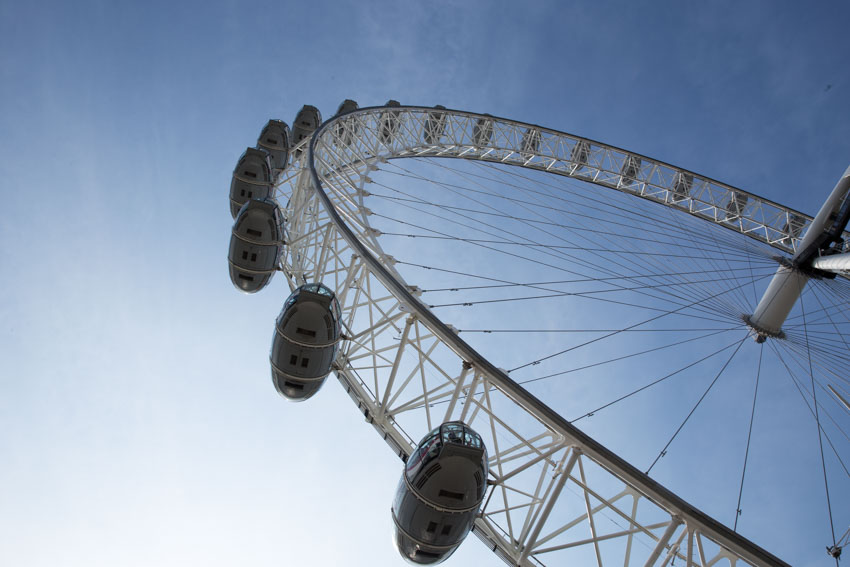 Extreme low angle shot of London Eye ferris wheel with blue sky background