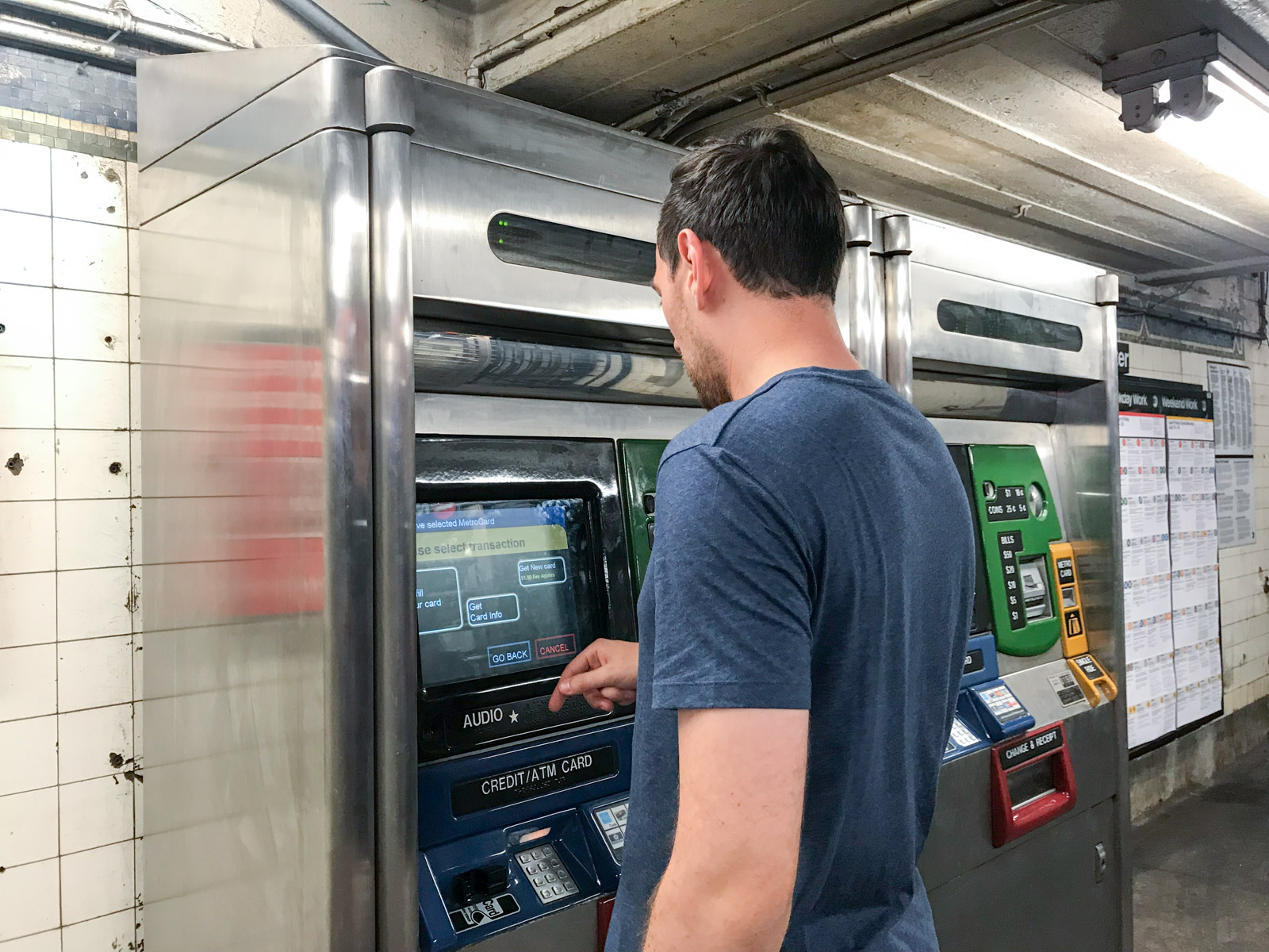 A man using a ticket machine to purchase subway tickets
