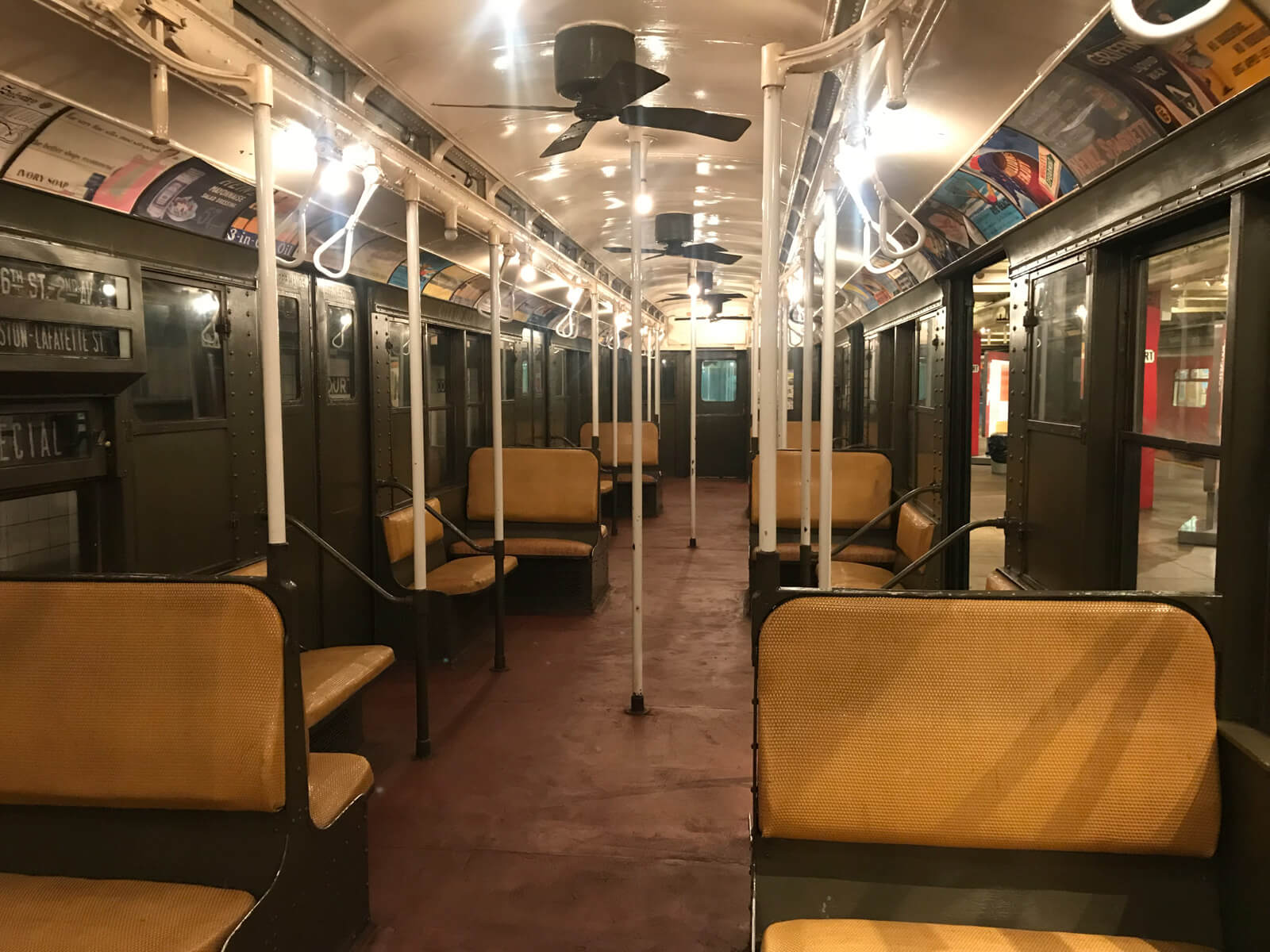 The inside of an old train carriage, with seats that have cushions covered in plastic straw