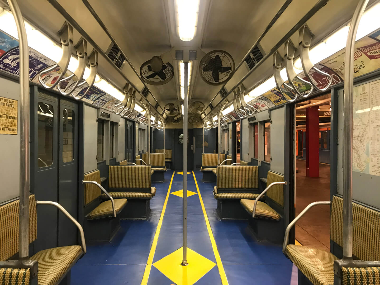 The inside of a different train carriage with a blue and yellow floor