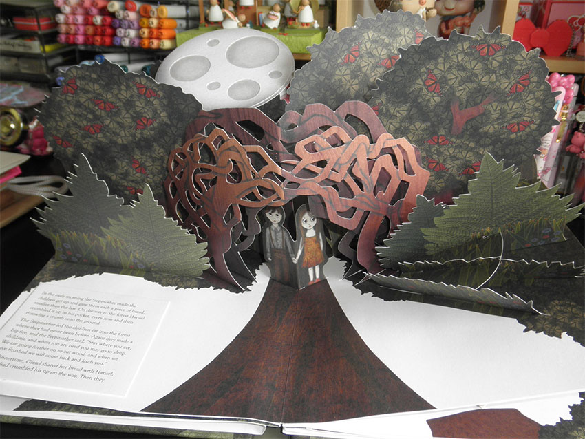 A cute pop-up book open to a page with a vertically-standing tree