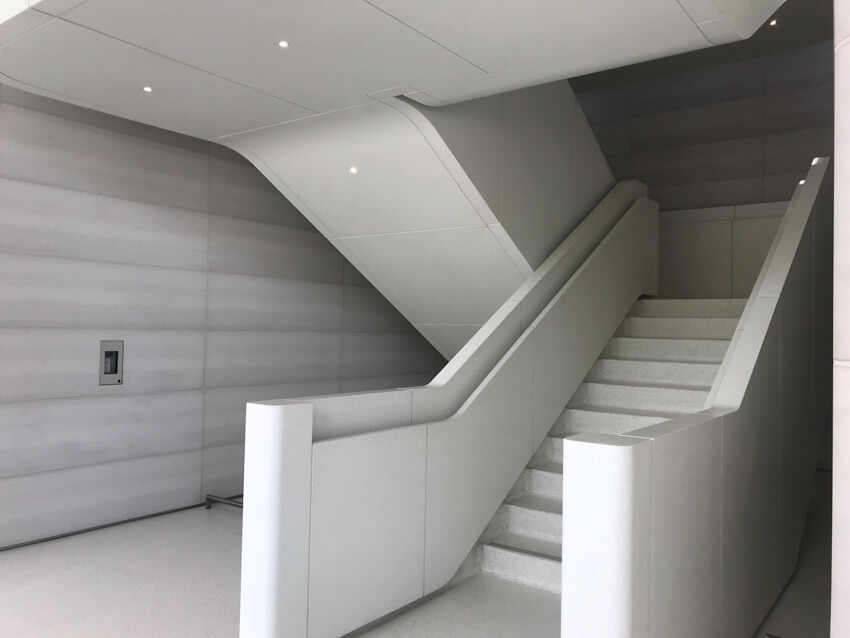 A staircase in white, with handrails built into the sides. The stairs change direction and there is no distinct pillar in the centre of the stairs.