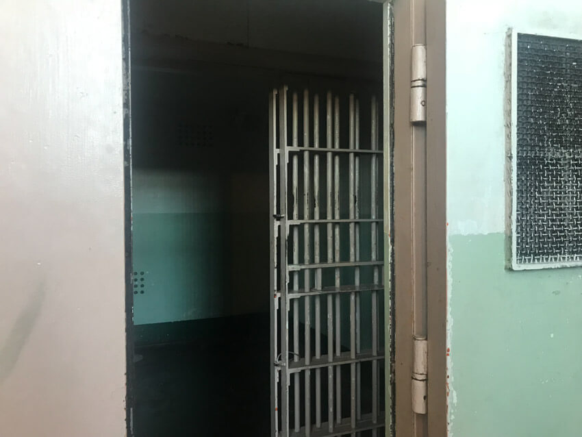 The door to a very dark jail cell with no light source apart from the entrance.