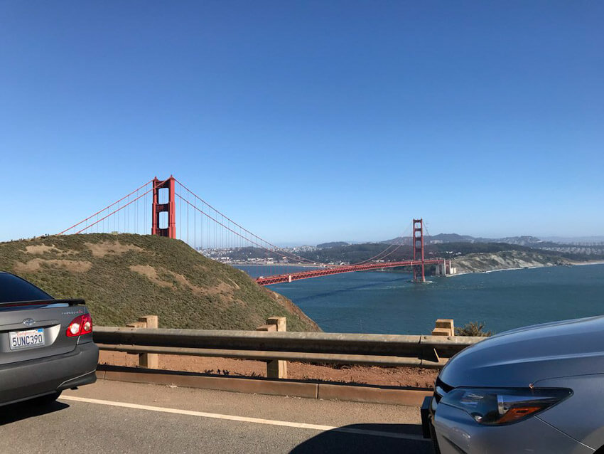 The Golden Gate Bridge in San Francisco as seen from a road at a higher altitude. The sky is very blue and it’s a clear afternoon.