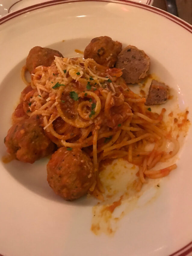 A white plate of spaghetti and meatballs