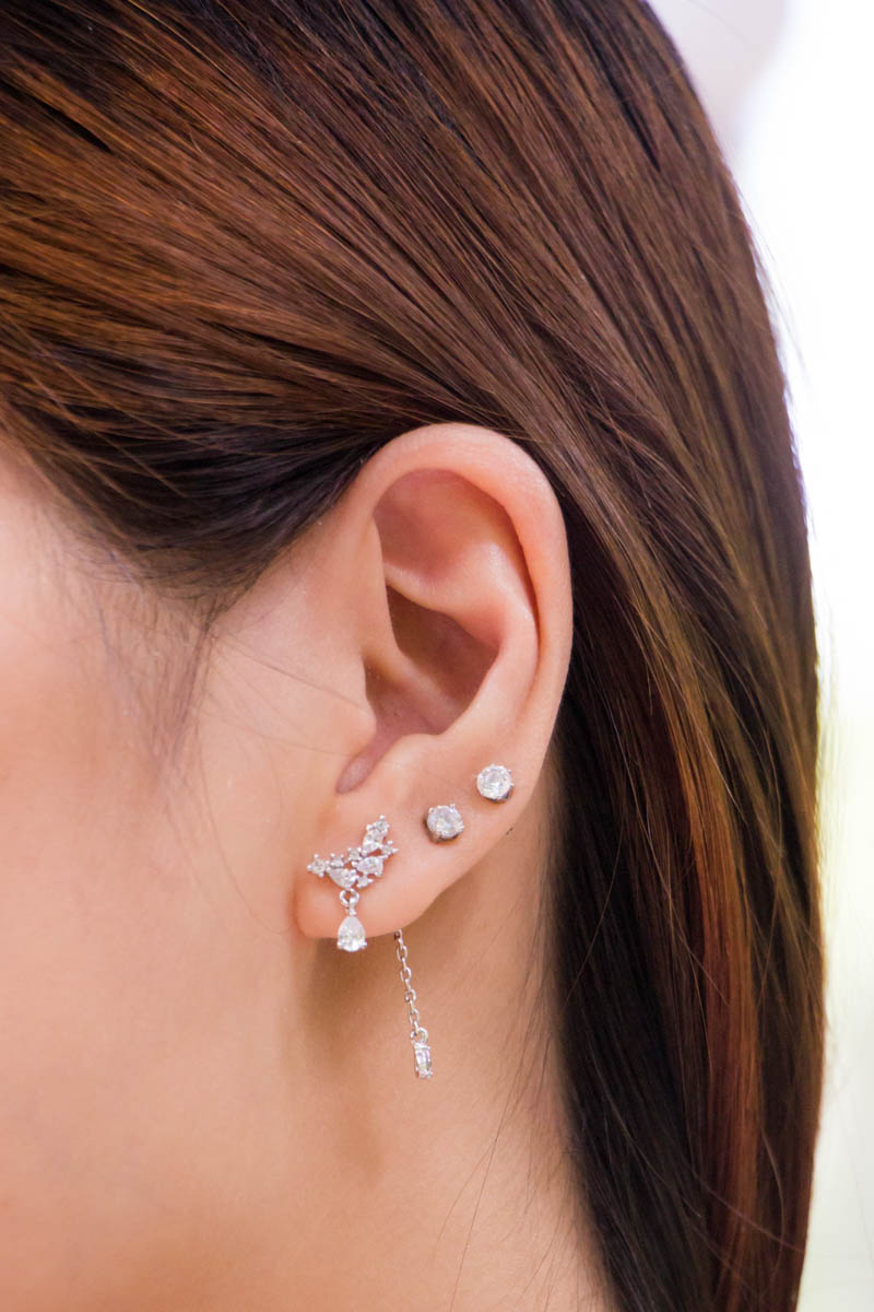 A close-up of the earrings, which have a chain drop backing