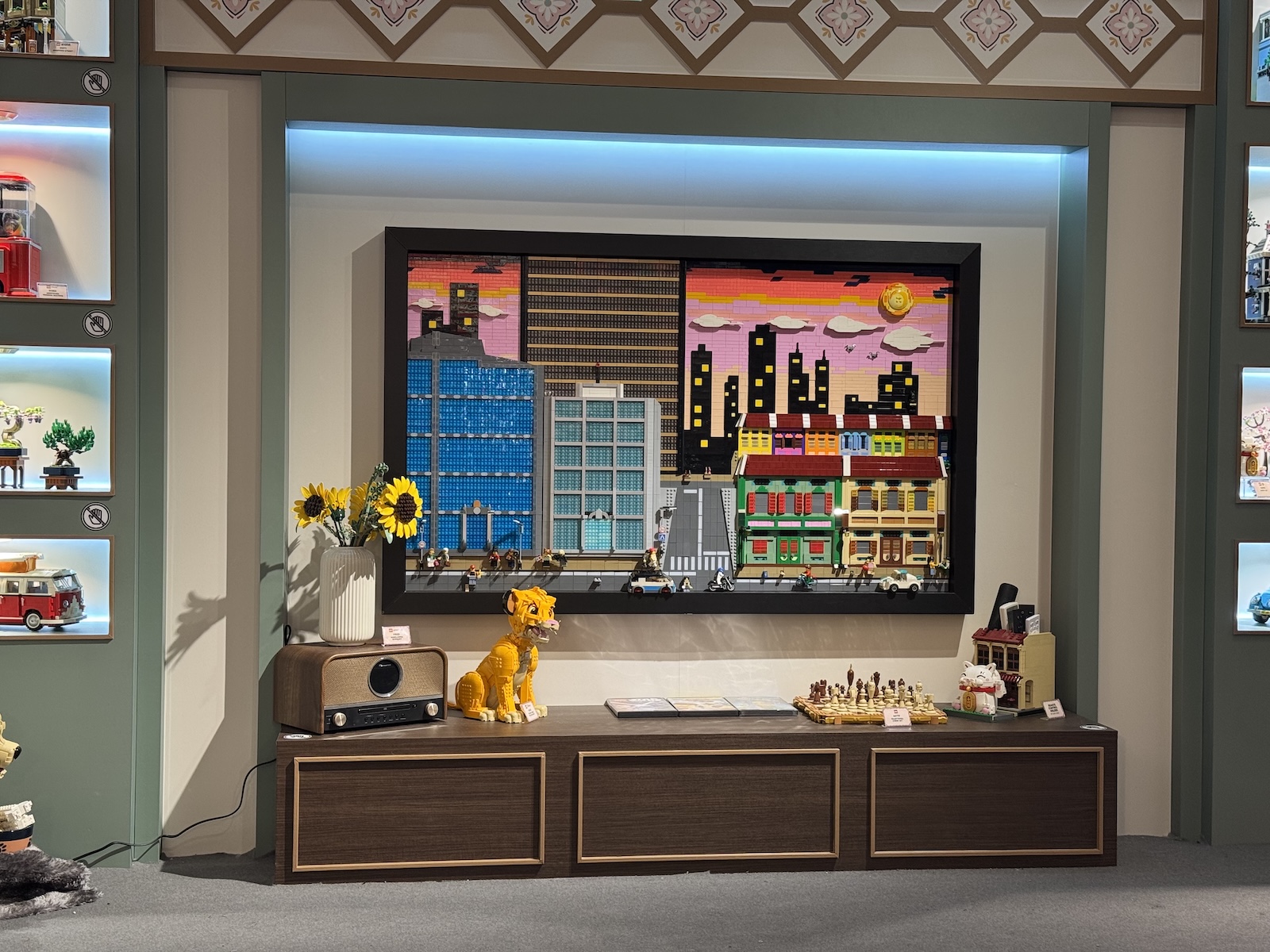 Mid-century console beneath a large framed pixel-art cityscape, made entirely of LEGO