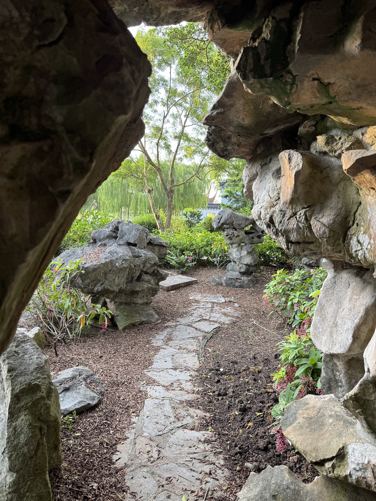 Stone path winding through a rocky grotto and lush garden.