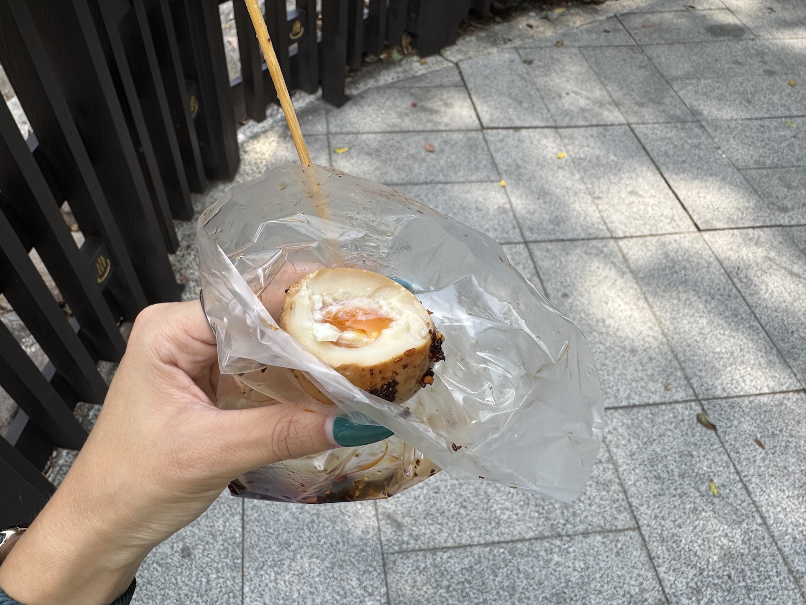 A person’s hand holding a soft boiled egg in a small plastic bag, showing the yolk of the egg