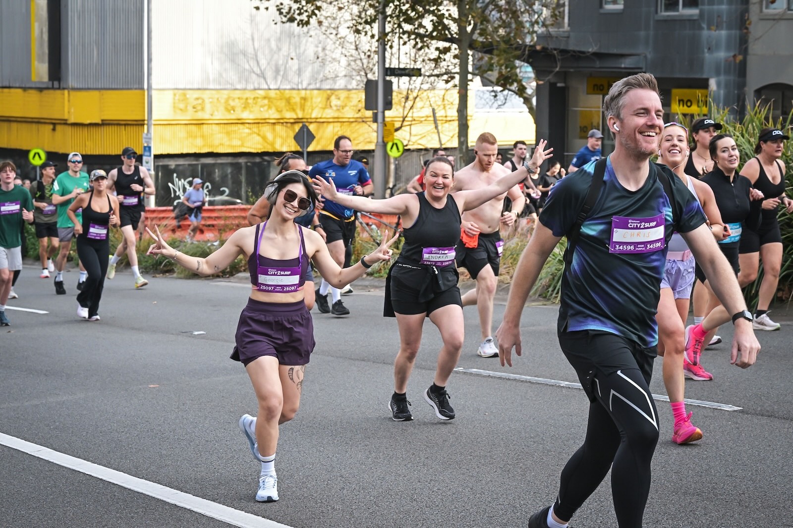 A group of City2Surf participants runs along the street, including myself wearing purple and wearing sunglasses, and Chris wearing black, both of us smiling