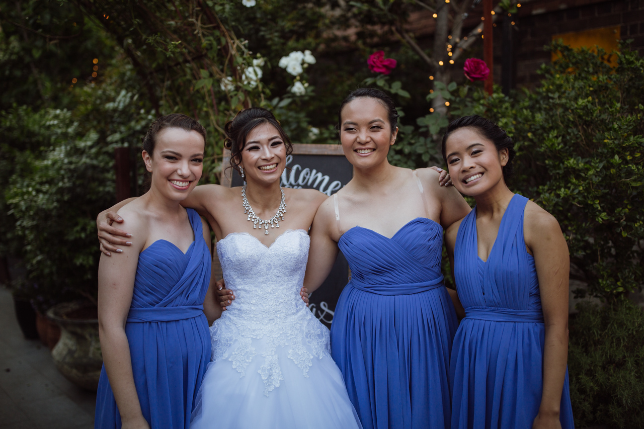 A bride in a white strapless dress with three bridesmaids in blue dresses