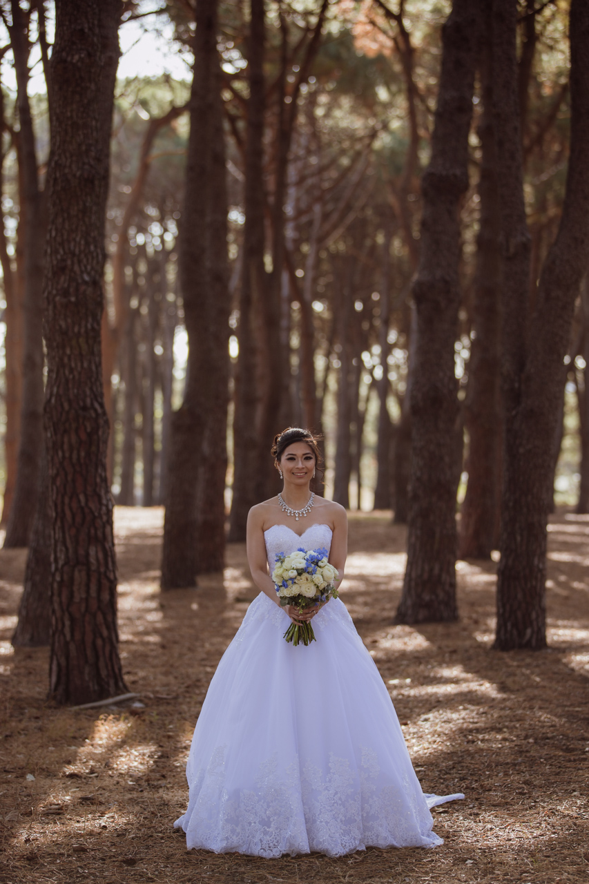 A bride in a white strapless ballgown holding a bouquet of off-white roses and blue flowers