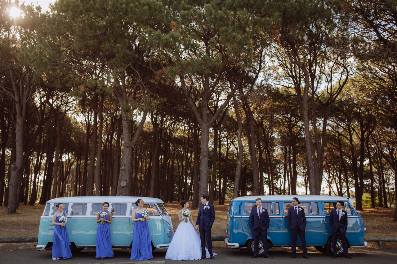 A bride and groom and their bridal party in front of two camper vans