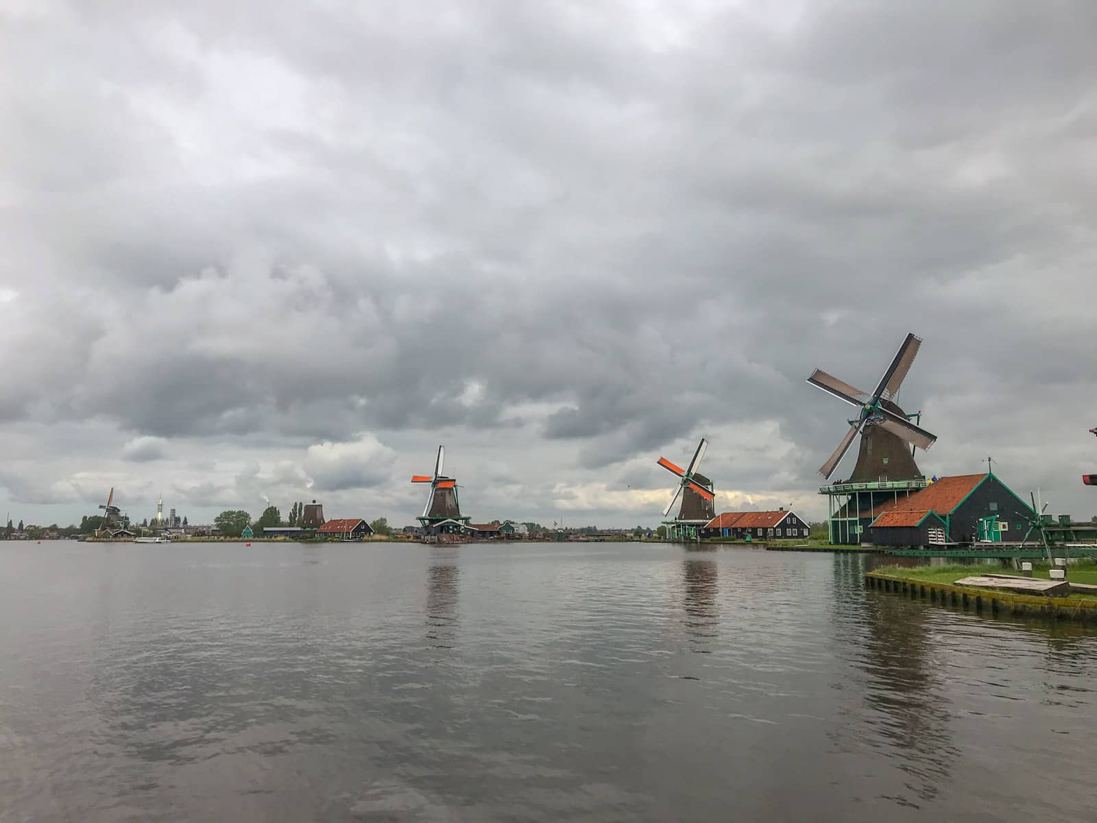 Several windmills spread out across land, seen from the opposite side of a river