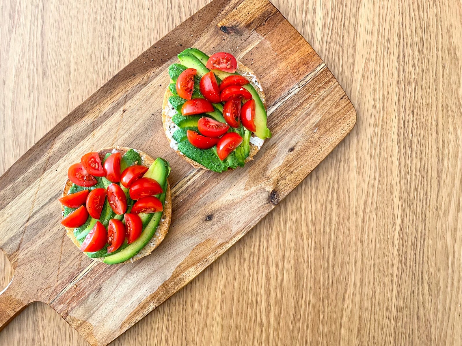 A wooden board on a wooden table, served with sliced avocado and wedges of sliced tomato