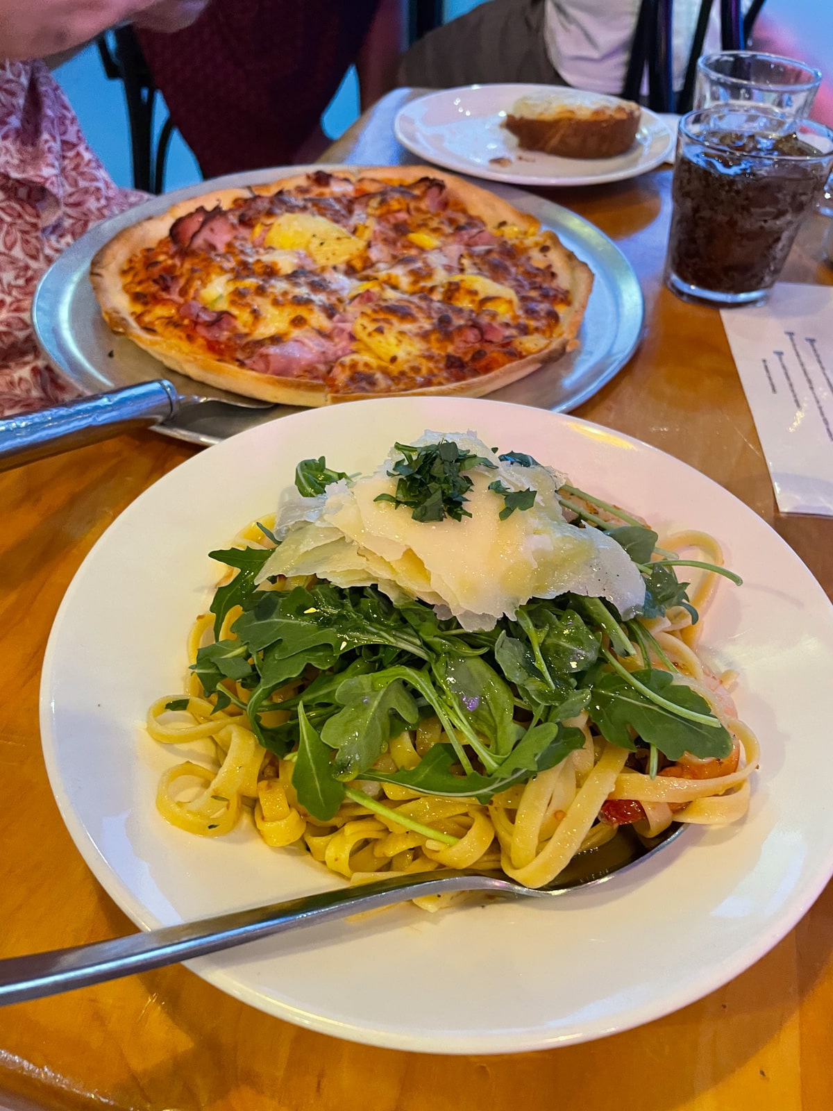 A bowl of linguine pasta cooked with chilli oil, dressed with rocket and garnished with parmesan and parsley