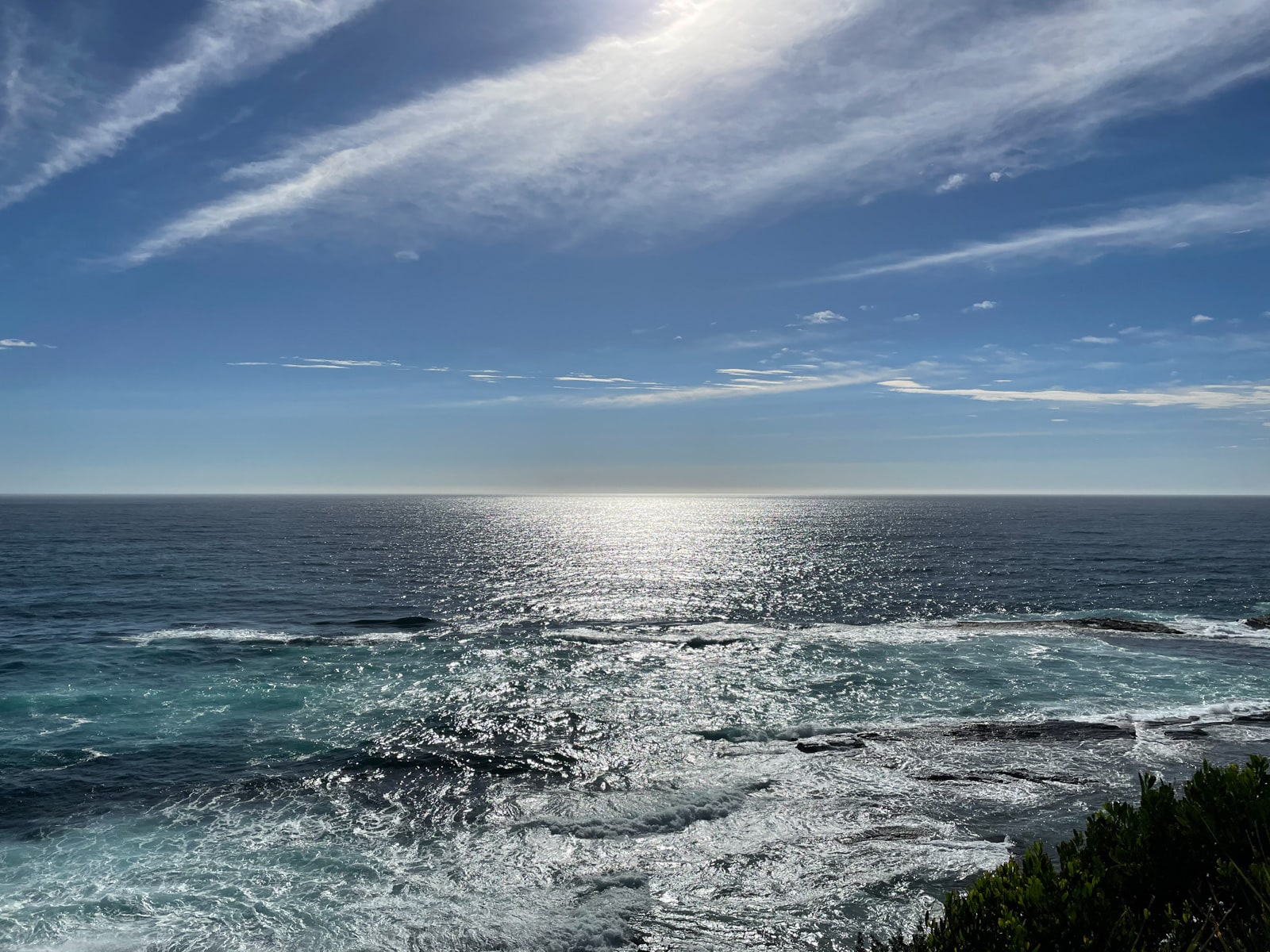 A view of the ocean, with the sun reflecting strongly on the water’s surface. The water has some movement in it.