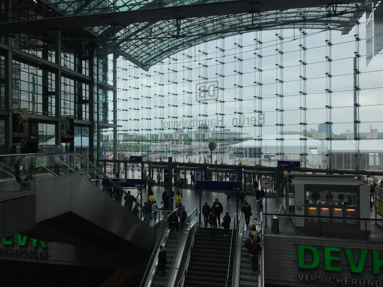 The inside of a train station with escalators visible, and an entire glass surface showing the outside of the station