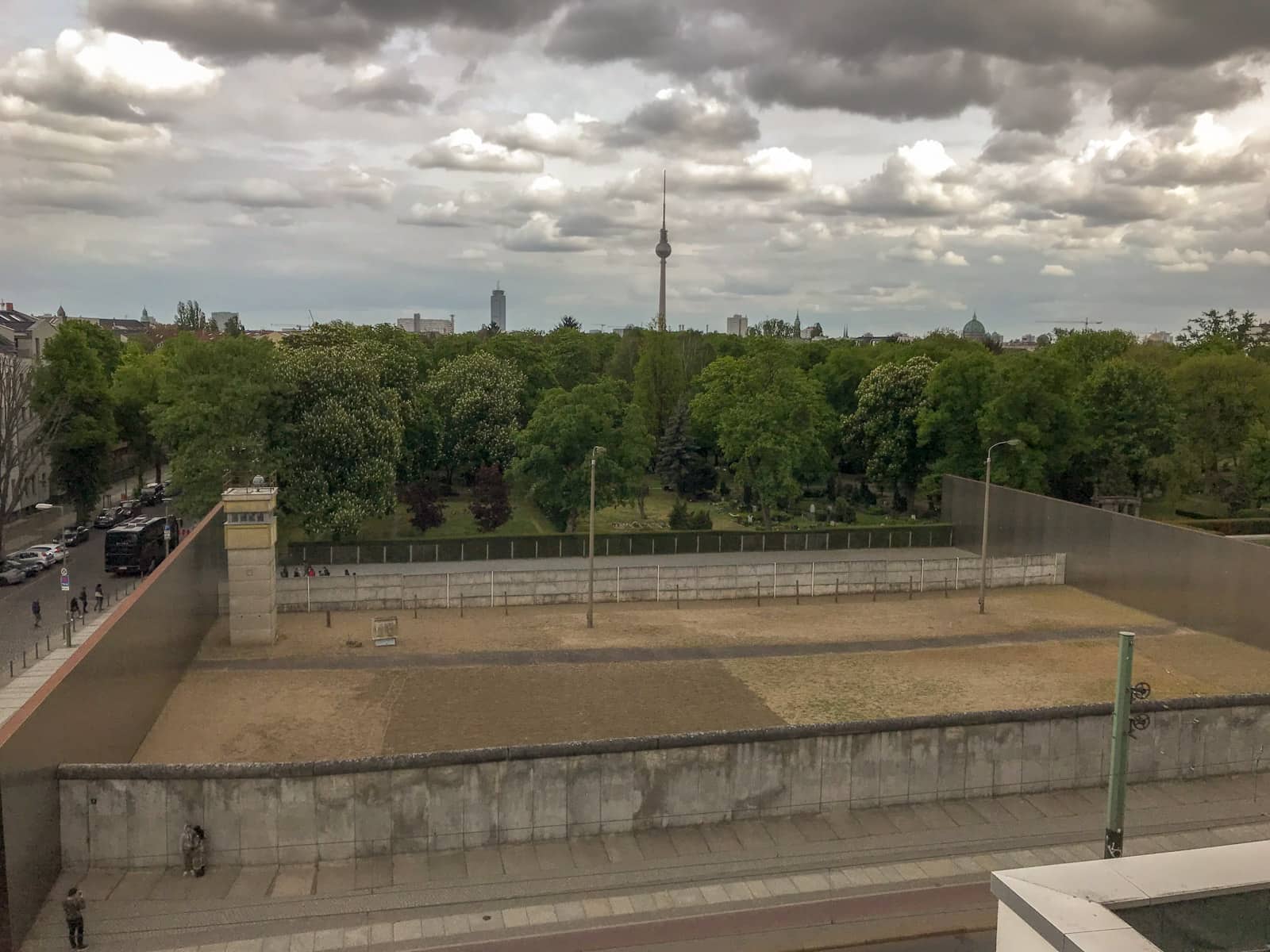 A section of the Berlin Wall and sectioned areas with wire fencing, blocked off by walls on all sides for preservation, all seen from a high vantage point.