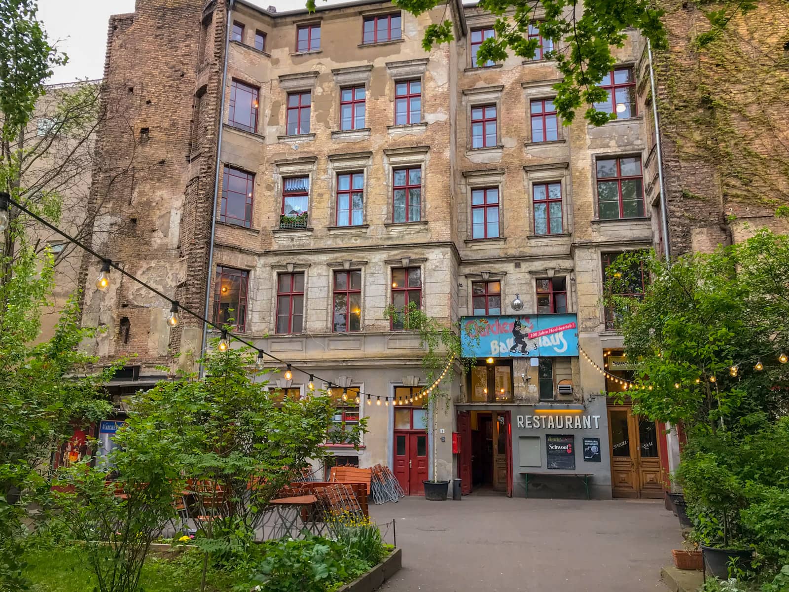 A courtyard with an old building in the background,and a lot of greenery in the courtyard