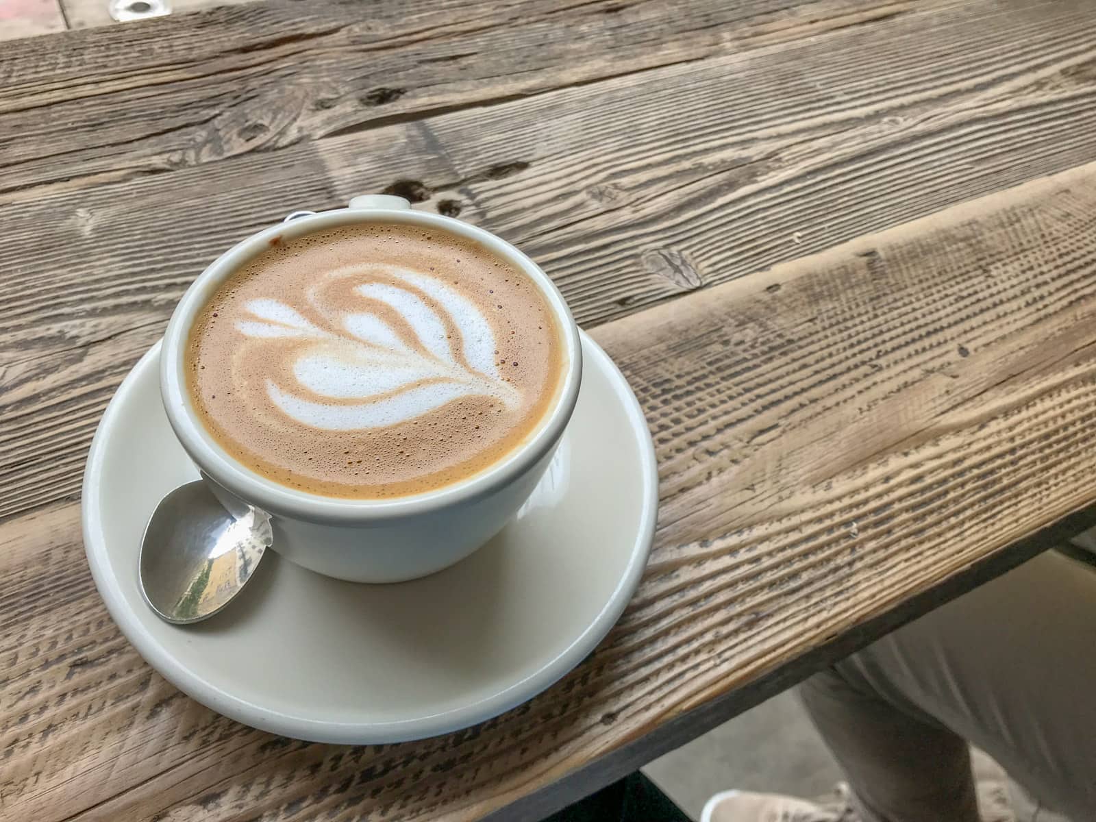 A cup of coffee with coffee art, on a wooden table