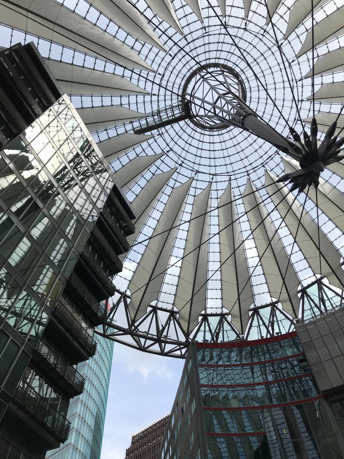 A view from the bottom of a building, showing the modern architecture of the building and the architecture of the roof, which lets light in