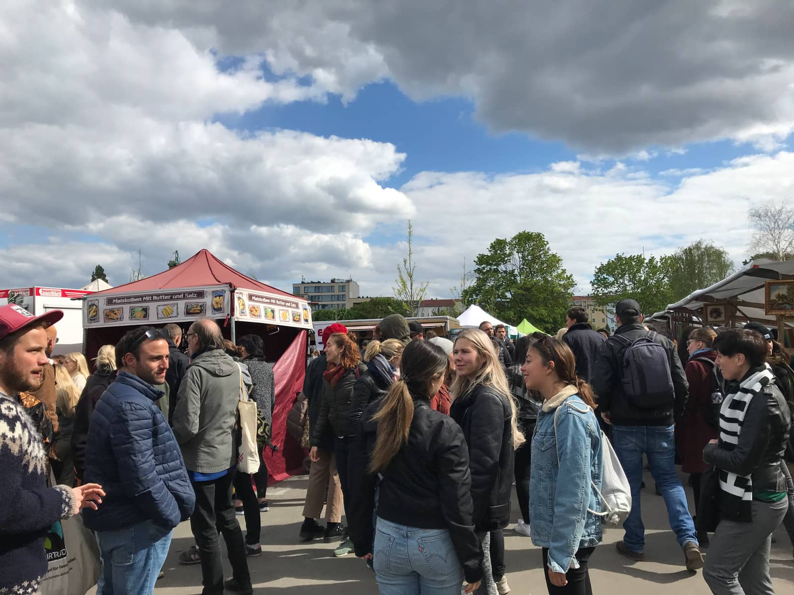 A small crowd of people in front of a couple of rows of food stalls.