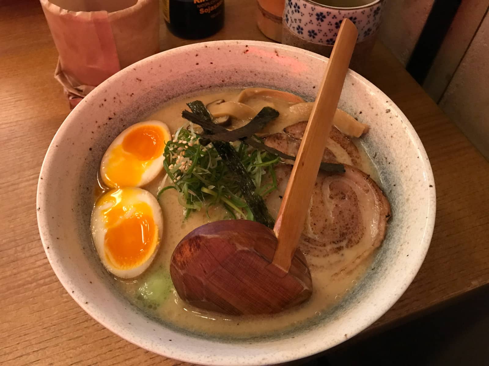A bowl of ramen with egg, dry seaweed, and sliced pork