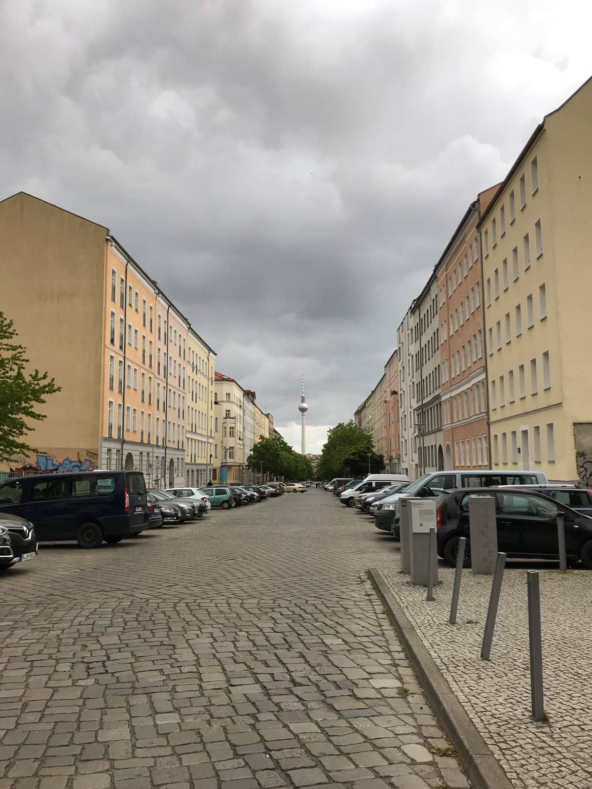A view of the Berlin television tower as seen from far away, down a quiet side street