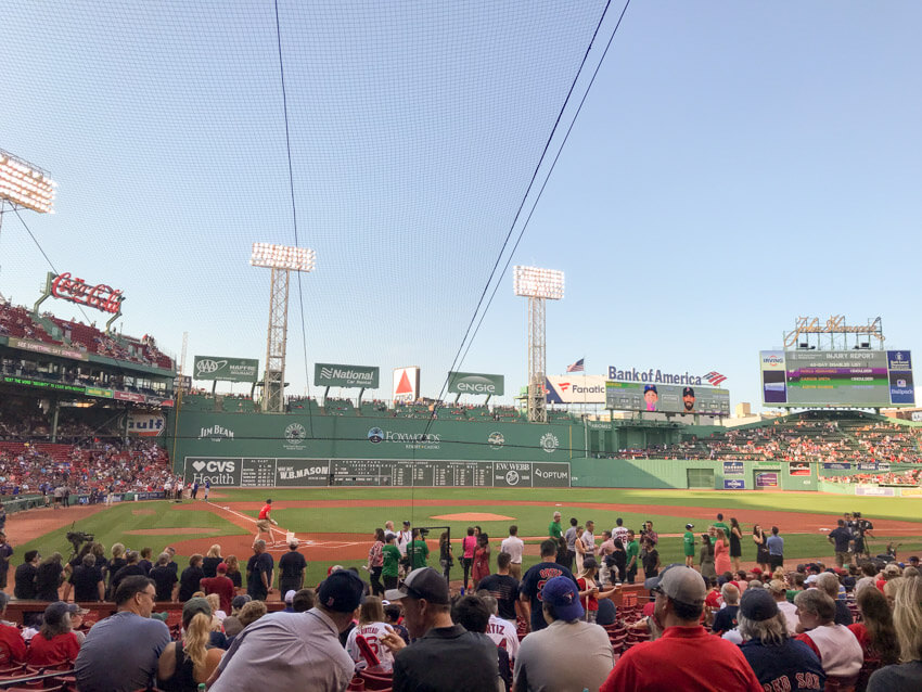 The inside of a baseball stadium with many seated spectators. Some media and other personnel are on the pitch, and the game has not yet commenced