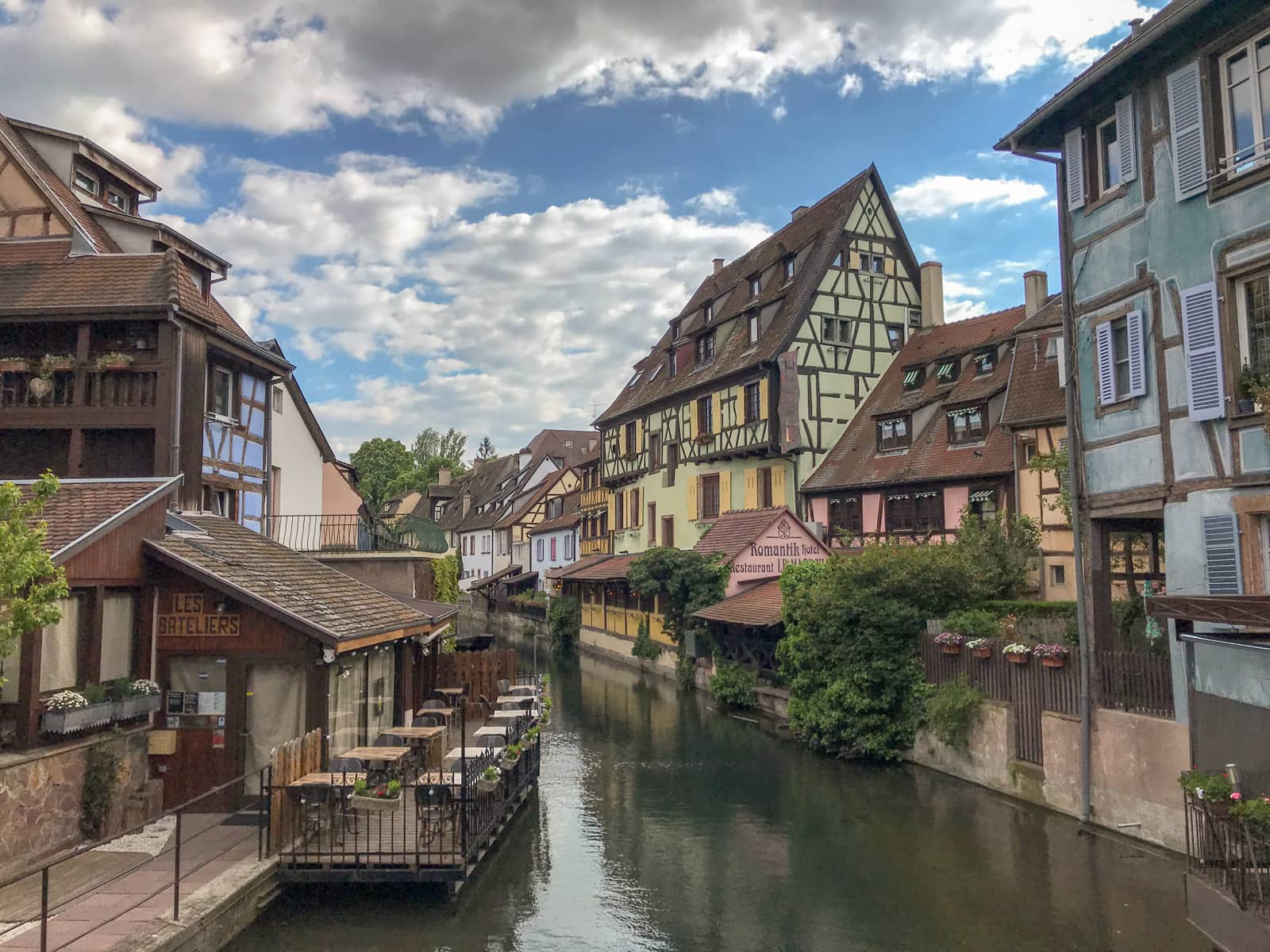 A view of a river going between two banks where old, colourful houses are erected, in the city of Colmar, France