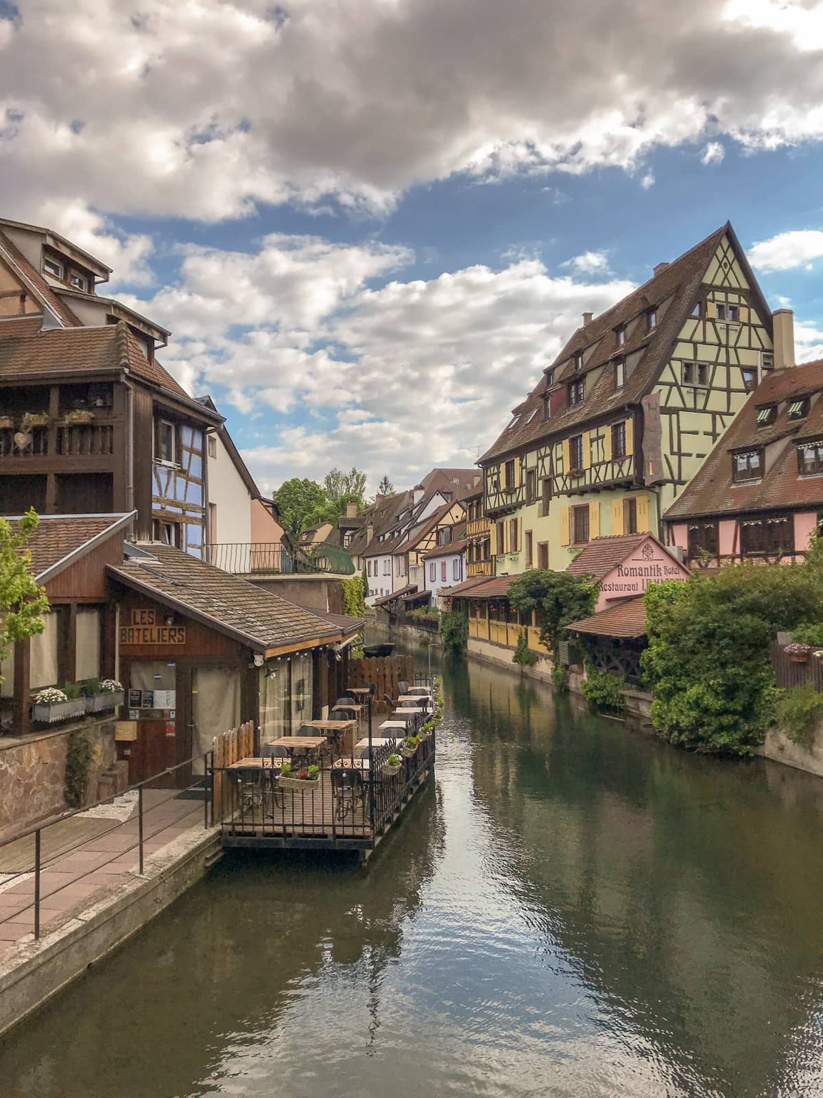 A view of a river going between two banks where old, colourful houses are erected, in the city of Colmar, France