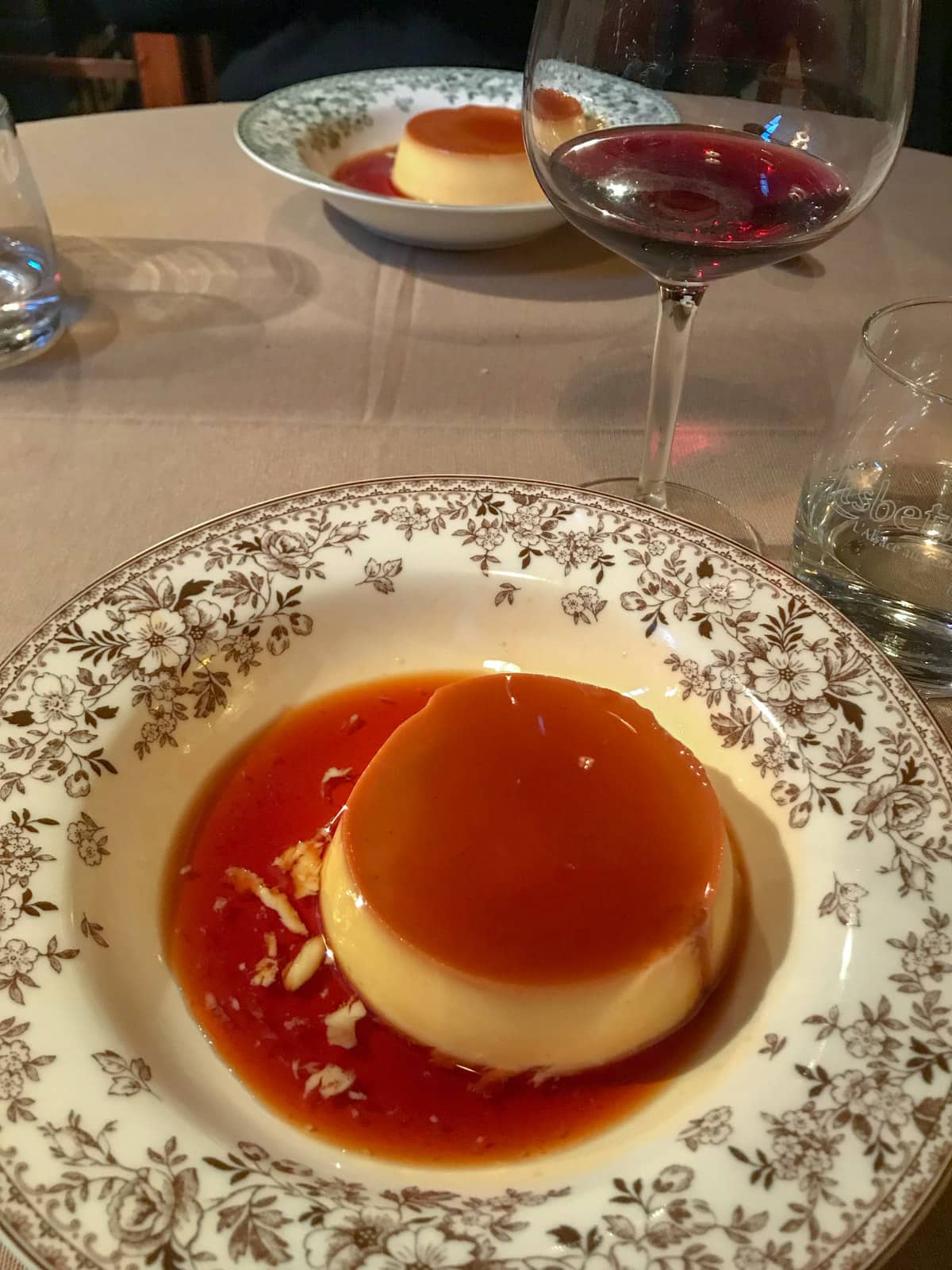 A shallow bowl with a dessert of caramel pudding with lots of caramel sauce