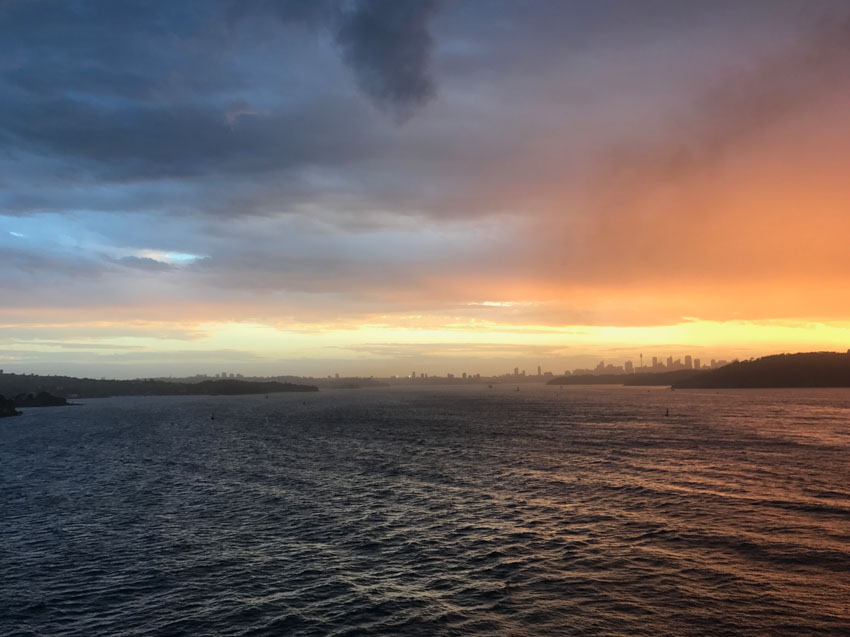 The sun setting on the water with Sydney city in the distance