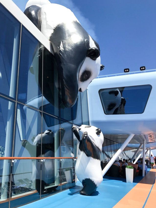 Panda statues set up so the mother on the roof is reaching for its cub on the ground