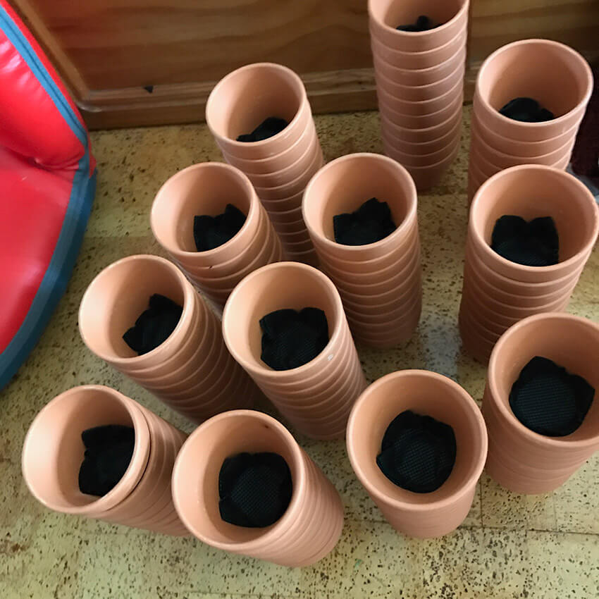 Twelve towers of small terracotta pots stacked together, each lined with black fabric