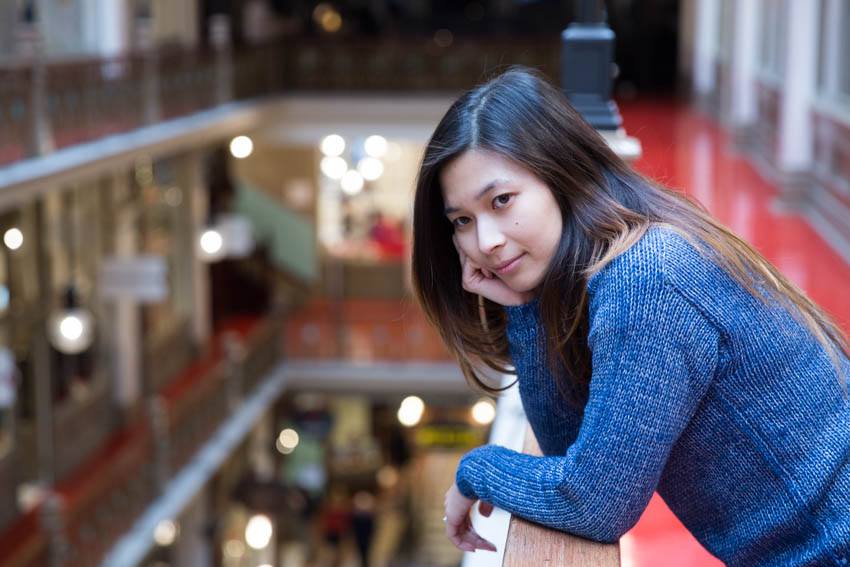 Close shot of me gazing away while leaning on the railing of a shopping mall level