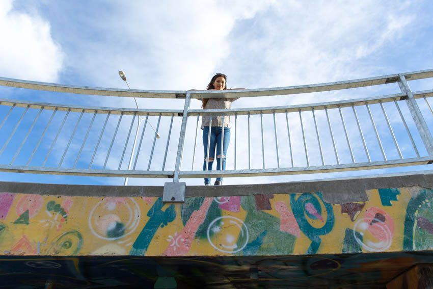 Closer shot of me leaning over a metal railing on an overpass