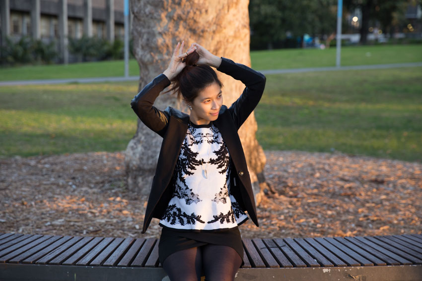 Me sitting on a wooden bench tying my hair in a ponytail